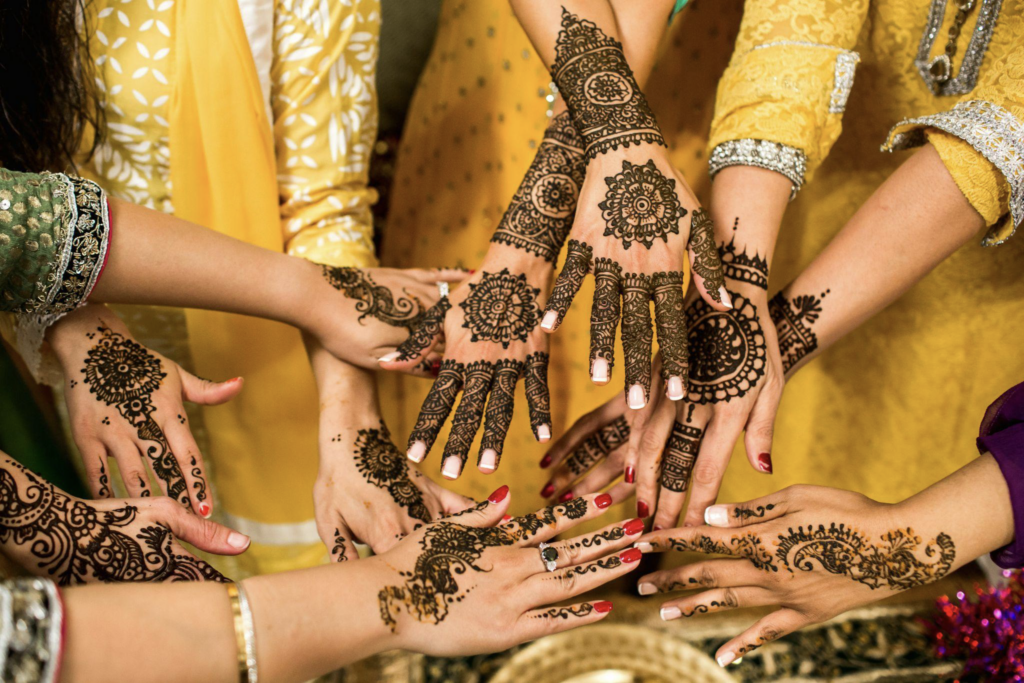 Indian Bridal Party Putting Hands Together with Henna Tattoos